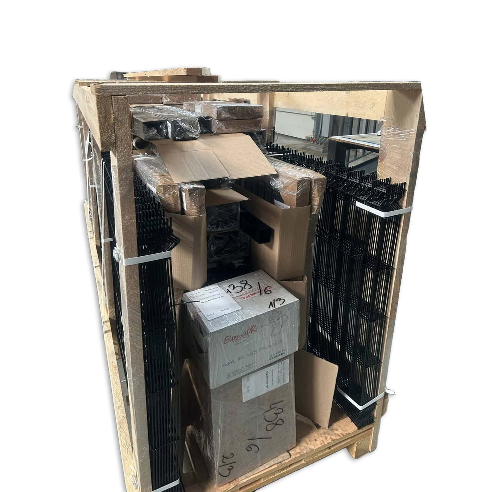 En stor trækasse til levering og fragt, indeholdende stablede metalreoler, papkasser og forskellige dele, alt sammen fastgjort med plastikfolie og stropper, isoleret på en hvid baggrund.