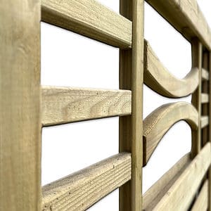 Nærbillede af en Havelåge m/espalier trykimpr. med lodrette og vandrette lameller. Hegnets tekstur og korn er tydeligt synlige, hvilket giver det et rustikt udseende. Nogle af de vandrette lameller er let buede. Baggrunden er hvid.