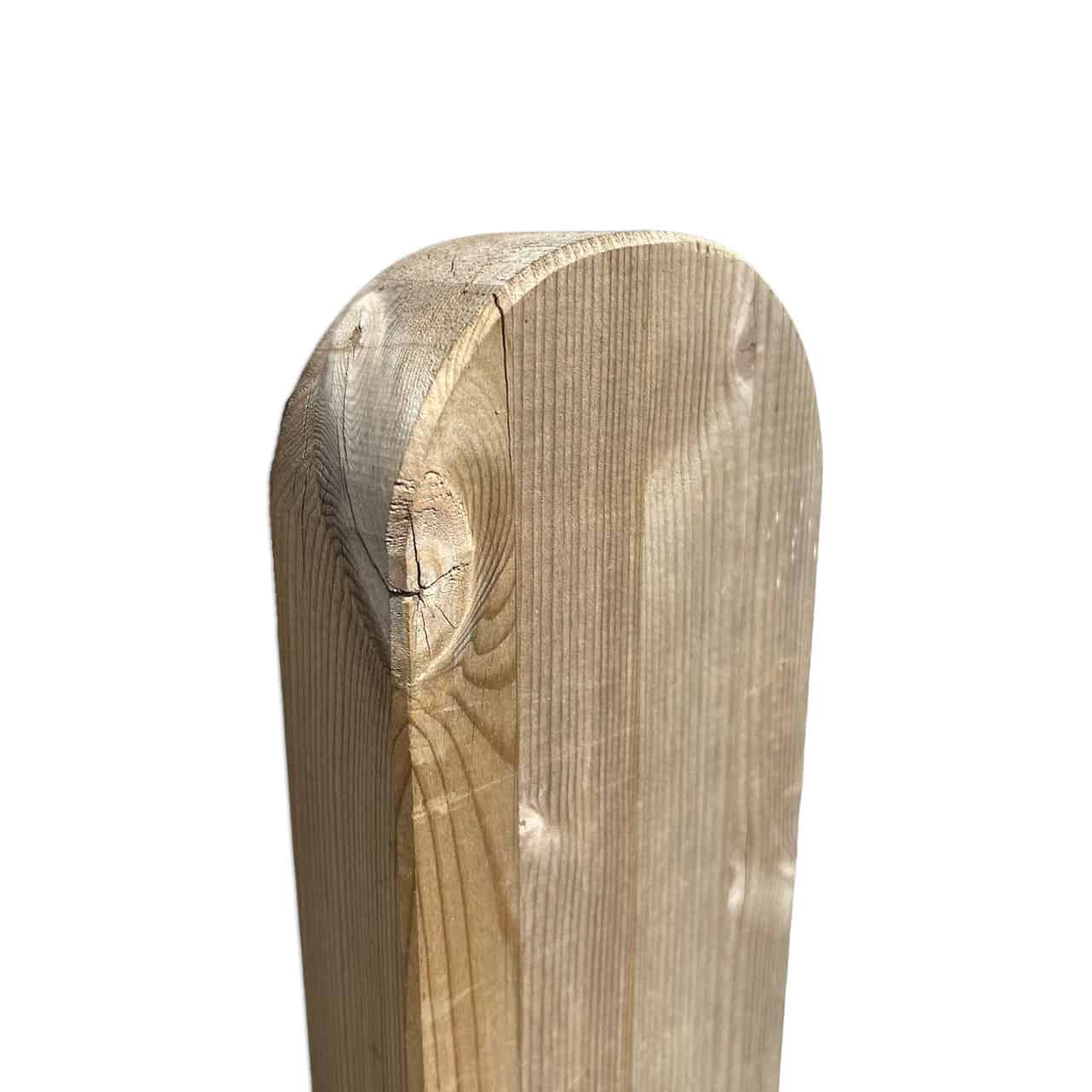 Nærbillede af den øverste del af en hegnspæl med en afrundet kant, almindeligvis brugt til fremstilling af en Havelåge ramme trymimpr. Træets årer og tekstur er tydeligt synlige, sammen med nogle naturlige knaster i træet. Baggrunden er helt hvid, hvilket gør indlægget til billedets eneste fokus.