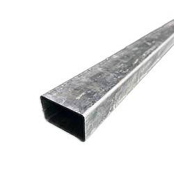 Et nærbillede af et langt, rektangulært metalrør med en firkantet hul sektion. Stålstolper 60x40mm / 2mm Varmgalvaniseret - Uden beslag ser ud til at have en galvaniseret, let ru overflade. Den er placeret diagonalt med den åbne ende vendt mod nederste venstre hjørne af billedet.