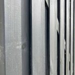 Nærbillede af et udsnit af en Havelåge Antracit 180x100cm malet i mørkegrå. Billedet fanger teksturen af de lodrette planker og træets årer. Perspektivet er let vinklet og viser dybde og kontrast mellem plankerne.