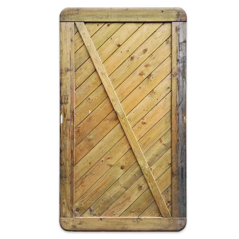 En høj, rektangulær Havelåge trykimpr trædør med diagonalt plankedesign og kant. Træet fremstår forvitret med en blanding af lyse og mørkere toner, der viser naturlige årer og knaster. Dørrammens kanter er afrundede, der ligner en rustik port.