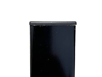 Nærbillede af den øverste del af en sort rektangulær genstand, eventuelt et møbel eller udstyr, med en glat, skinnende overflade. Stolpehatte 60x40 mm Plast Flad skiller sig tydeligt ud mod den almindelige hvide baggrund.