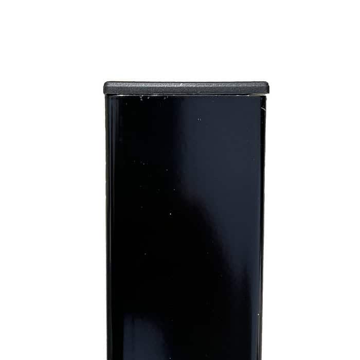 Nærbillede af den øverste del af en sort rektangulær genstand, eventuelt et møbel eller udstyr, med en glat, skinnende overflade. Stolpehatte 60x40 mm Plast Flad skiller sig tydeligt ud mod den almindelige hvide baggrund.