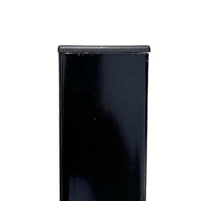 Nærbillede af den øverste del af en sort rektangulær genstand, eventuelt et møbel eller udstyr, med en glat, skinnende overflade. Stolpehatte 60x40 mm Plast Flad skiller sig tydeligt ud mod den almindelige hvide baggrund.