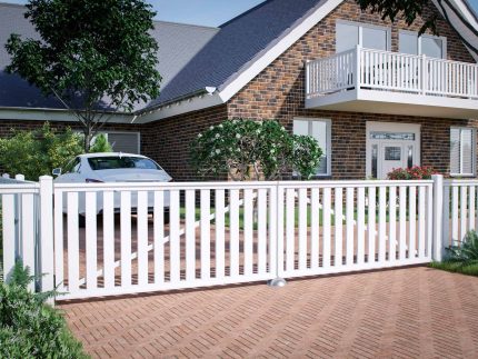 Et moderne murstenshus med et trekantet tag, en balkon med et slankt rækværk og store vinduer. Forgården har en asfalteret indkørsel, der fører til et hvidt plastik dobbeltlåge "Gelænder" mål 400x90cm (AVLET). Der er en hvid bil parkeret ved siden af huset, og grønne områder, herunder træer og buske, omgiver området.