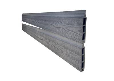To vinklede, grå, træteksturerede Kompositbræt 25mm - WPC Træstruktur er placeret diagonalt parallelt mod en hvid baggrund. Pladerne har en rillet sideprofil, der indikerer en hul indvendig struktur.