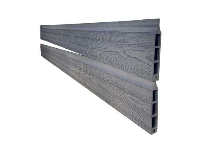 To vinklede, grå, træteksturerede Kompositbræt 25mm - WPC Træstruktur er placeret diagonalt parallelt mod en hvid baggrund. Pladerne har en rillet sideprofil, der indikerer en hul indvendig struktur.