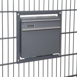 En slank, antracit 7016 mat Postkasse til indbygning i panelhegn er monteret i et metalhegn. Postkassen har en smal spalte til post og en hængslet klap nedenunder. Hegnet har et gittermønster, og kassen fastgøres med fire skruer, en i hvert hjørne af monteringsrammen.