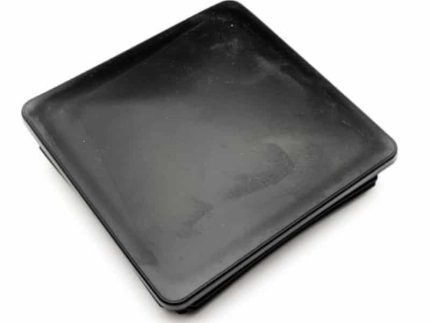 En firkantet sort plade med let hævede kanter, placeret på en hvid baggrund, har en glat, blank finish og ser ud til at være tom. Det slanke design minder om moderne arkitektoniske elementer som Plastik stolpehat til stålstolpe 100x100mm.
