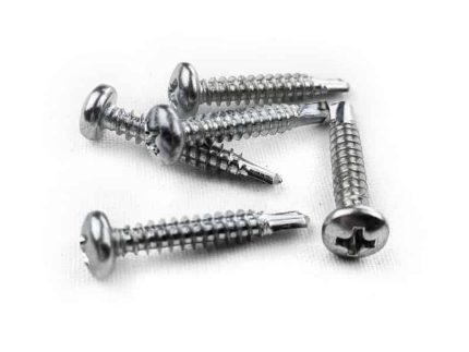 Et nærbillede af seks elforzinket selvskærende skruer med flade, slidsede hoveder og spidse ender liggende på en hvid overflade.