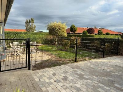 Et indhegnet område med et hegn og en have.