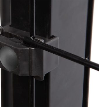 Et nærbillede viser en del af en metallisk sort ramme med en klemme, der fastgør en tynd sort stang til den. Klemmen, der ligner Punkt Beslag Sæt til 60x40 stolper/panelhegn, har en knap eller knop på siden. Billedet fokuserer på forbindelsespunktet og fremhæver fastgørelsesmekanismen.