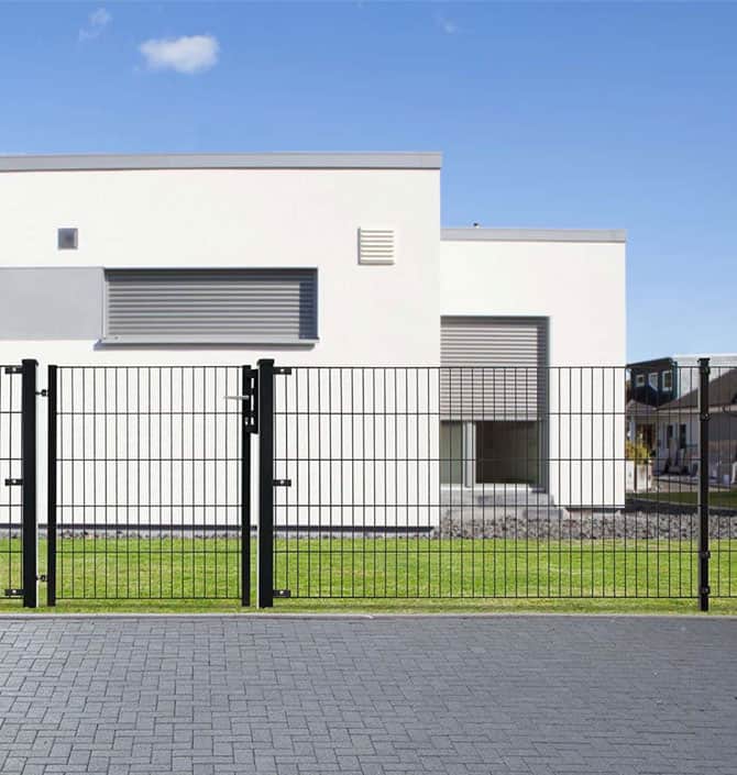 En moderne hvid bygning med store vandrette vinduer dækket af metalskodder, omgivet af et sort metalhegn og en murstensbelagt gangbro. Himlen er klar og blå, perfekt til at nyde det stærke trådløse netværk, der er tilgængeligt i hele ejendommen.