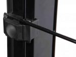 Nærbillede af Metal Stolpe "BLACKY" 60x40mm, med en sort låsemekanisme med en vandret metalstang, der passerer igennem den. Låsen fastgøres til den lodrette, pulverlakerede sorte metalstolpe, hvilket viser dens robuste og enkle design. Baggrunden er sløret, hvilket fremhæver låsens detaljer.