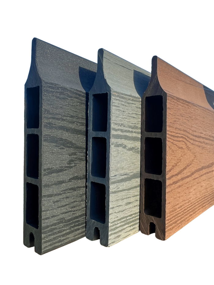 En række af tre Type 1-kompositterrassebrædder fra Komposit Hegn-kollektionen, med hule centre og vist lodret for at vise deres forskellige farver - mørkegrå, lysegrå og brun - fra venstre mod højre. Hvert bræt har en træstruktur på overfladen og er sat mod en almindelig grøn baggrund, hvilket gør dem ideelle til dit komposit hegn-projekt med galvaniserede stålstolper og U-kanaler.