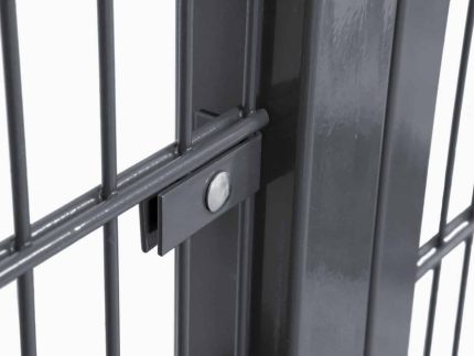 Nærbillede af Vinkelbeslag til midt stolpe - Låge, hegn og vægbeslag, der viser en sort metalport med lodrette stænger sikkert fastgjort af en central låsemekanisme, der holdes på plads af en cirkulær bolt. En nærliggende stolpe forstærker portens robuste konstruktion, mens dens blanke finish smukt reflekterer lyset.