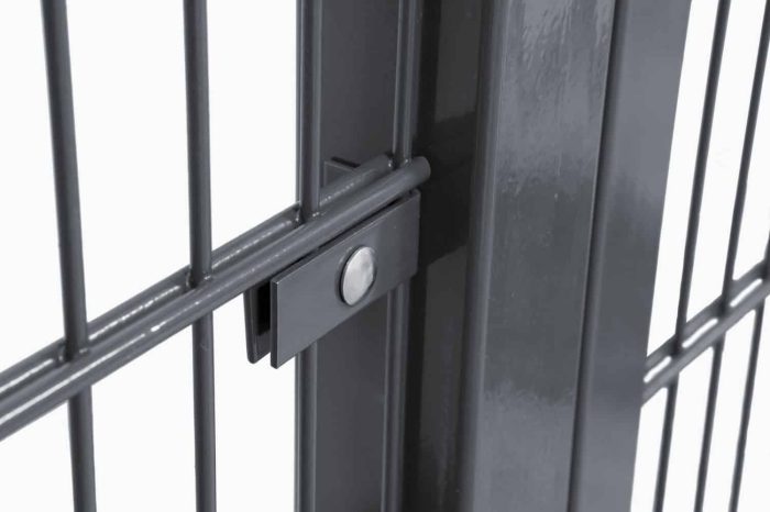 Nærbillede af Vinkelbeslag til midt stolpe - Låge, hegn og vægbeslag, der viser en sort metalport med lodrette stænger sikkert fastgjort af en central låsemekanisme, der holdes på plads af en cirkulær bolt. En nærliggende stolpe forstærker portens robuste konstruktion, mens dens blanke finish smukt reflekterer lyset.
