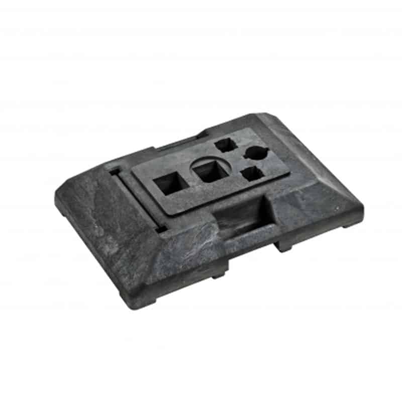 En mørkegrå, rektangulær industriel metalkomponent med forskellige formede udskæringer, herunder en firkant, en cirkel og en sekskant. Denne Fodplade LETVÆGT 18 KG til afspærringshegn fremstår som en maskindel eller værktøjsindsats mod en hvid baggrund.