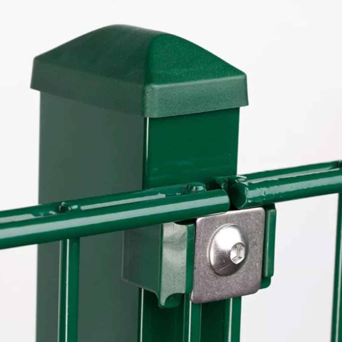Nærbillede af en grøn metal hegnspæl med en hætte og en vandret stang fastgjort ved hjælp af en Holdeplade med hul - Rustfrit stål beslag og bolt. Baggrunden er almindelig hvid, hvilket fremhæver posten og dens forbindelseskomponenter.