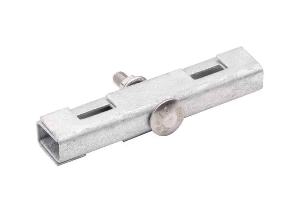 En galvaniseret metallisk klemme med en justerbar skrue og to slidsede åbninger. Designet giver mulighed for sikker fastgørelse på strukturer. Den er lagt på en hvid baggrund.