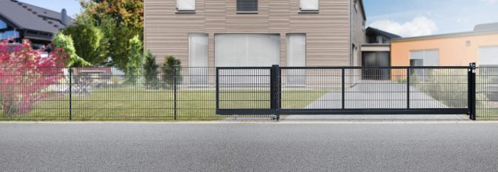 Et moderne bolighus kan prale af en stor flad indkørsel, en smukt anlagt gårdhave og en slank sort metal Skydeport "LIGHT" skydeport, der spænder over 3 til 4,5 meter. Huset har store vinduespartier med en kombination af træ og grå paneler. Det gennemtænkte design suppleres af farverige planter og levende grønne områder i gården for at forbedre dens visuelle appel.