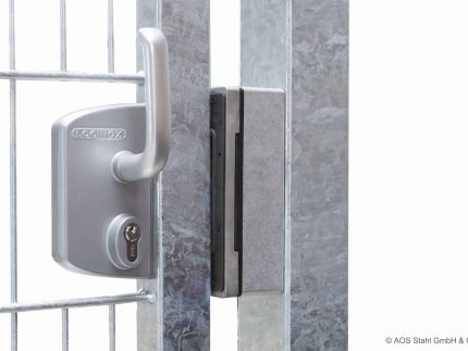 Nærbillede af en sølv hegnslåge med et Locinox-låsesystem i rustfrit stål påsat. Porten, med Skydeport "V-Star EXTREME" 2D Panelfyld 8/6/8 MM, holdes sikkert af låsen installeret på metalrammen. Låsen har en nøglecylinder og et håndtag. © AOS Stahl GmbH & Co. KG.