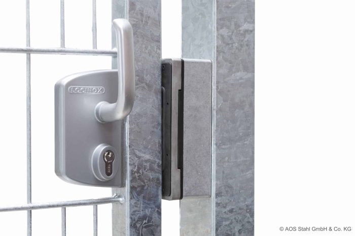 Nærbillede af en sølv hegnslåge med et Locinox-låsesystem i rustfrit stål påsat. Porten, med Skydeport "V-Star EXTREME" 2D Panelfyld 8/6/8 MM, holdes sikkert af låsen installeret på metalrammen. Låsen har en nøglecylinder og et håndtag. © AOS Stahl GmbH & Co. KG.