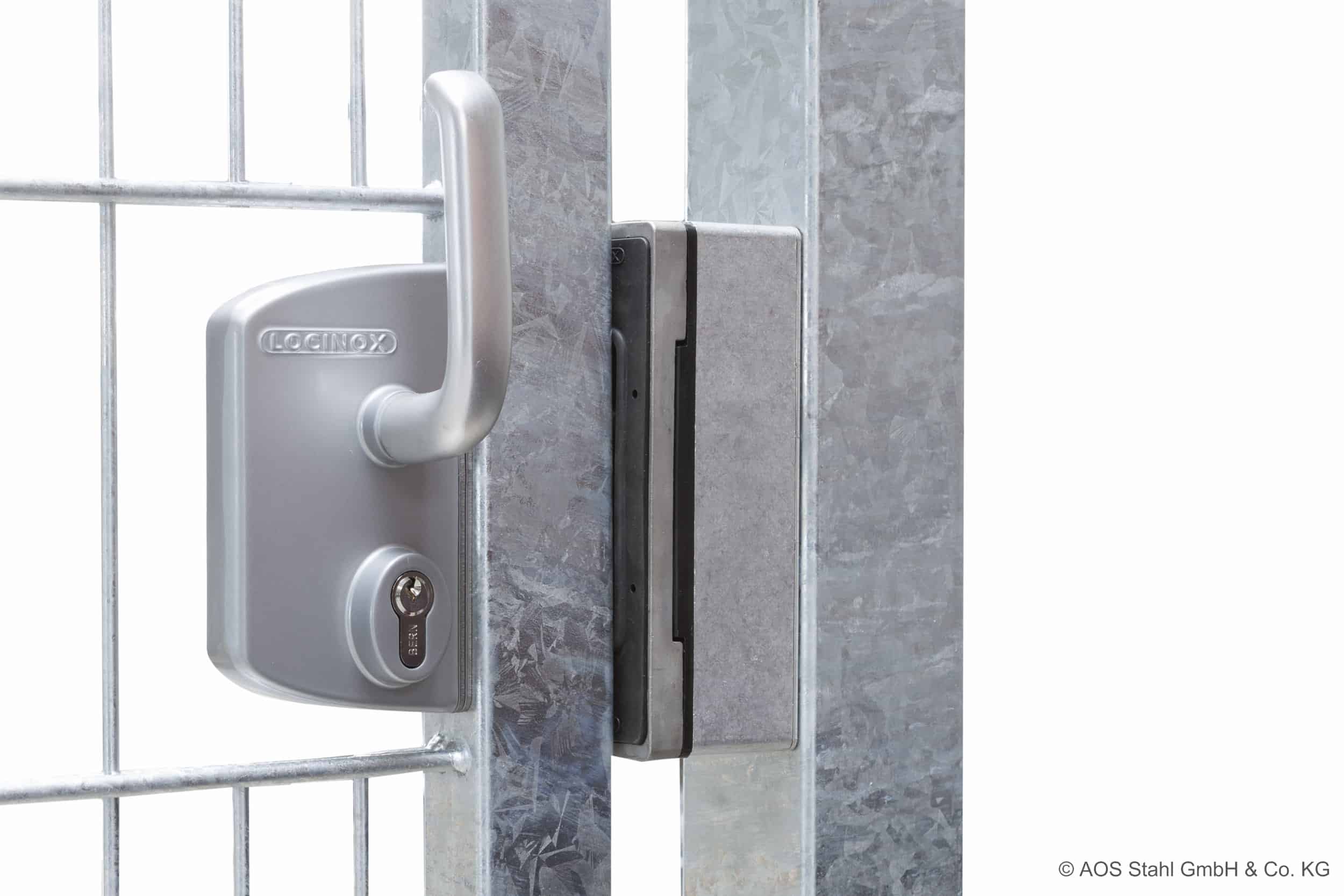 Nærbillede af en sølv hegnslåge med et Locinox-låsesystem i rustfrit stål påsat. Porten, med Skydeport "V-Star EXTREME" 2D Panelfyld 8/6/8 MM, holdes sikkert af låsen installeret på metalrammen. Låsen har en nøglecylinder og et håndtag. © AOS Stahl GmbH & Co. KG.
