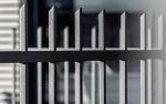 Nærbillede af Baluster Hegn Pulverlakeret Antracit Metal - Inkl. Stålstolper & Beslag, med lodrette stænger. De mørke metalstænger er jævnt fordelt og har en let struktureret overflade. Baggrunden er sløret, hvilket fremhæver hegnets struktur.