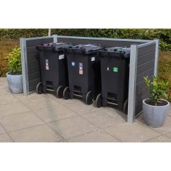 Tre sorte skraldespande på hjul med farvede låg er pænt arrangeret i en børstet sort Komposit skraldespandsskjul. To potteplanter sidder i hjørnerne af indhegningen, som er sat på en flisebelagt terrasse med grønt løv i baggrunden.