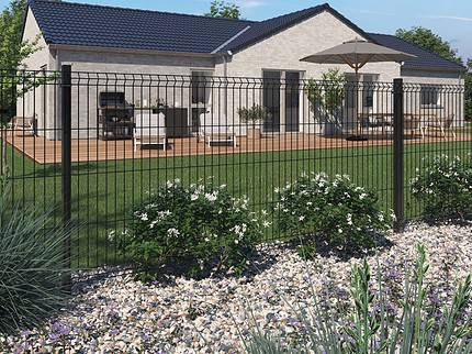 Et moderne etplanshus med lys beige ydervægge og mørkt spåntag. Huset har en rummelig træterrasse med udendørsmøbler og en paraply. En velholdt græsplæne med klippehave og Metal Hegn 3D Panel "HF-BUDGET SERIES" Inkl. Stålstolper & Beslag - Pulverlakeret Sort omkranser huset.