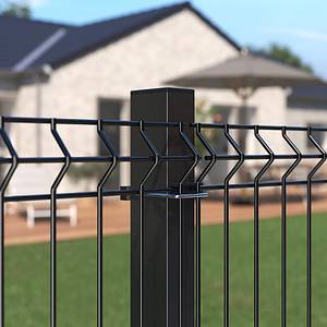 Detaljeret visning af et Metal Hegn 3D Panel "HF-BUDGET SERIES" Inkl. Stålstolper & Fittings i Pulverlakeret Sort, med et geometrisk design, med en velholdt græsplæne i forgrunden og et moderne et-plans hus med et stort dæk og udendørsmøbler i baggrunden. Den klare himmel indikerer, at det er en solskinsdag.