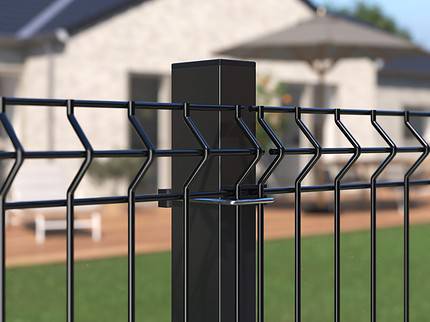 Detaljeret visning af et Metal Hegn 3D Panel "HF-BUDGET SERIES" Inkl. Stålstolper & Fittings i Pulverlakeret Sort, med et geometrisk design, med en velholdt græsplæne i forgrunden og et moderne et-plans hus med et stort dæk og udendørsmøbler i baggrunden. Den klare himmel indikerer, at det er en solskinsdag.