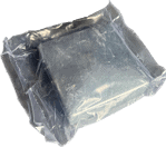 En firkantet, mørkegrå genstand lavet af Stolpehat Varm galvaniseret stål HDG 80x80mm er forseglet i en gennemsigtig plastvakuumemballagepose. Emballagen fremstår tæt og sikker og viser nogle reflekser og små krøller på plastoverfladen. Objektet indeni ser solidt og uigennemsigtigt ud.