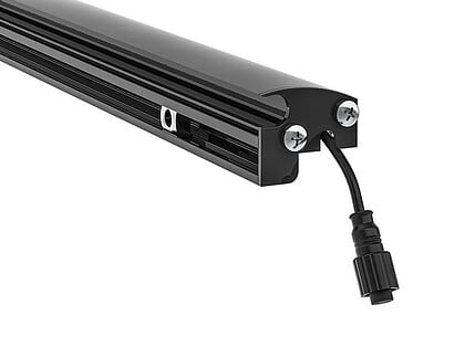 Nærbillede af enden af en sort cylindrisk LED-Lysliste "LightUp" til Panelhegn, med et tilsluttet strømkabel med et cirkulært stik. Lysstangen har to synlige skruer og et monteringsbeslag til at fastgøre den. Designet er slankt og minimalistisk med en blank finish.