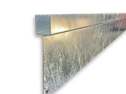 Et nærbillede af Bundplade Galvaniseret Stål - 1815x175x35/2mm trimstykke afslører dens Z-formede profil. Den teksturerede overflade, der sandsynligvis har en bundpladebelægning eller prægningsmønster, skiller sig ud mod den almindelige hvide baggrund og understreger beklædningens metalliske glans og strukturelle detaljer.