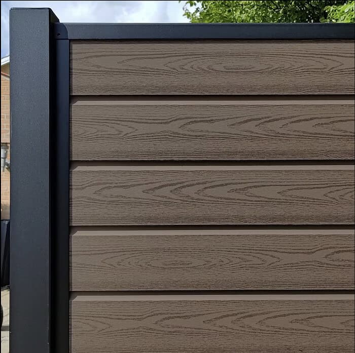 Et plankeværk med vandrette planker og en sort metalramme giver en elegant kontrast, der ligner en Komposit Hegn med sorte pulverlakeret stålstolper & u-skinner - Type 1. Træets naturlige årer komplementerer træet ovenover, mens en murstensvæg titter igennem til venstre.