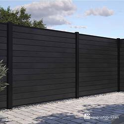 Et moderne hegn bygget af vandrette sorte planker med lodrette sorte stolper er afbildet. Dette hegn, kendt som "Komposit Hegn med sorte pulverlakeret stålstolper & u-skinner - Type 1," omslutter et udendørs område med en asfalteret grund og noget synligt grønt i baggrunden. "Hegnsfabrikken"-logoet er placeret i nederste højre hjørne af billedet.