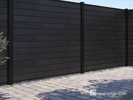 Et moderne hegn bygget af vandrette sorte planker med lodrette sorte stolper er afbildet. Dette hegn, kendt som "Komposit Hegn med sorte pulverlakeret stålstolper & u-skinner - Type 1," omslutter et udendørs område med en asfalteret grund og noget synligt grønt i baggrunden. "Hegnsfabrikken"-logoet er placeret i nederste højre hjørne af billedet.