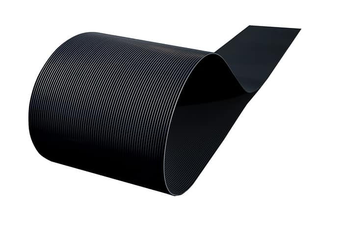 Et nærbillede af en sort POLYFIX Afskærmning rulle 26 m SORT RAL 9005 - Indfletning af Panelhegn, der viser dens fleksible og parallelle linjer, der danner en glat kurve mod en hvid baggrund. Kablets tekstur og ensartede linjer er fremtrædende i billedet, der ligner en slank hegnsstrimler.