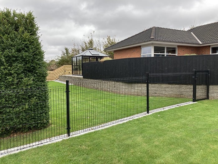 3D Panelhegn i pulverlakeret sort i en have.