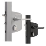 To dørlåse af metal, herunder en Locinox overflademonteret låsekasse komplet, er monteret på lodrette flader - en sølvfarvet med et matchende håndtag og en sort med et matchende håndtag, begge med nøglehuller under håndtagene.