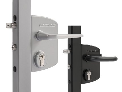 To dørlåse af metal, herunder en Locinox overflademonteret låsekasse komplet, er monteret på lodrette flader - en sølvfarvet med et matchende håndtag og en sort med et matchende håndtag, begge med nøglehuller under håndtagene.