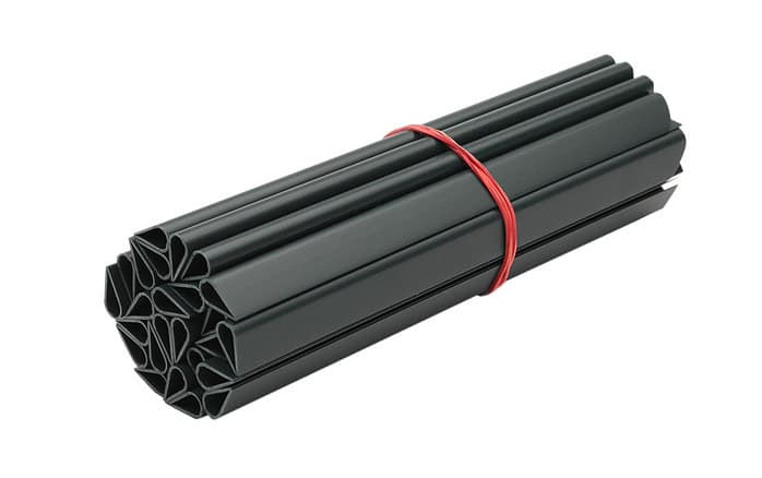 Et bundt Klemmeskinner Sort PVC til Afskærmningsruller (1 stk.) i mørkegrå, lavet af blød PVC, holdes sammen med et rødt gummibånd. Ekstrusionerne er formet til et mønster med nogle stjernelignende former og er tæt pakket sammen.