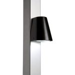 Vi præsenterer Design LED Belysning til Hegn og Porte - Locinox TRICONE, en slank og moderne vægmonteret lampe med en sort konisk skærm fastgjort til en lodret, metallisk overflade. Med LED-belysning leder dette lys belysningen nedad, perfekt til accentbelysning.