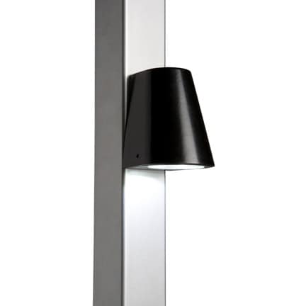 Vi præsenterer Design LED Belysning til Hegn og Porte - Locinox TRICONE, en slank og moderne vægmonteret lampe med en sort konisk skærm fastgjort til en lodret, metallisk overflade. Med LED-belysning leder dette lys belysningen nedad, perfekt til accentbelysning.