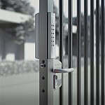 En slank VOLTA - Overflademonteret lås med eksternt batteridrevet tastatur med numerisk tastatur pryder metalporten, sat mod en sløret udendørs scene af træer og bygninger.