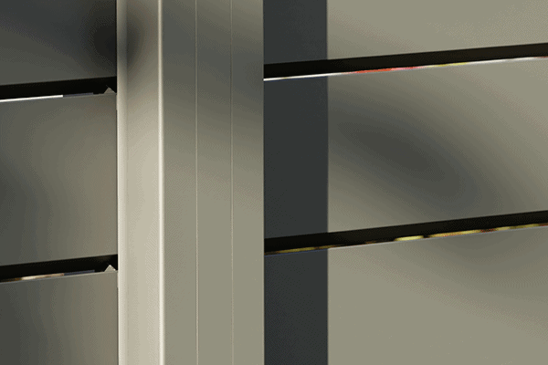 Nærbillede af Vidual Pure – Jalousihegn i aluminium med rhombeprofil i lysegrå, med vandrette lameller med sollys, der kaster skygger langs det moderne hegns overflade.
