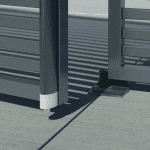 Nærbillede af en moderne metalport med vandrette lameller med Locinox Bundstop til dobbeltlåger – justerbart og overflademonteret (RAL 9005). Det justerbare hængsel og den overflademonterede base er synlige, da porten står let åben på beton.